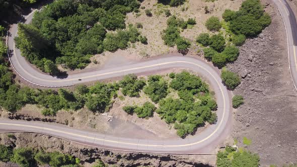 Aerial top down static view of motorcycle riding on a spectacular scenic horseshoe hairpin bend road