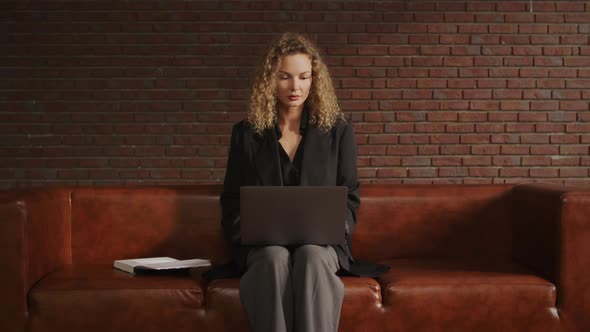 Young Adult Businesswoman Working on a Laptop in a Loft Apartment