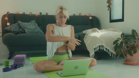 Woman Doing Stretching on the Floor at Home in Front of Her Laptop Online Yoga Class