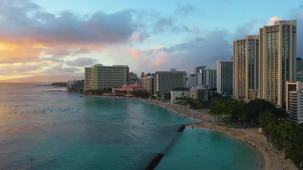 Hawaiian Beach Surfers and Tourists Near Beachfront Resort Hotel Buildings Swimming and Relaxing in