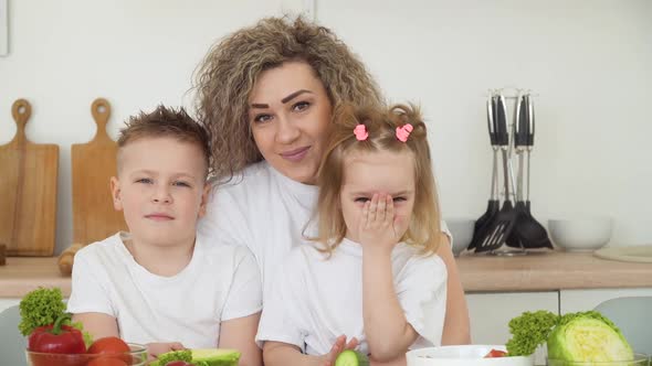 Children with Mom Sitting at a Table in a Bright Kitchen