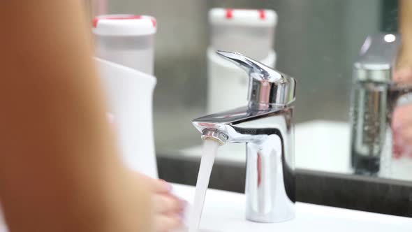 Person Washes Hands From Automatic Soap Dispenser in Bathroom Closeup