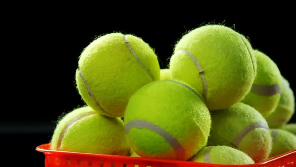 Basket full of tennis ball against black background