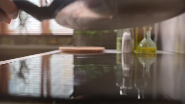 Cook Puts the Frying Pan on the Stove to Warm Up