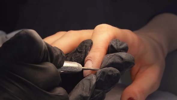 Closeup of Manicurist's Hands in the Black Gloves Removing Old Nail Gel Polish