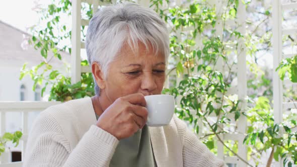 Happy senior mixed race woman enjoying a coffee in garden