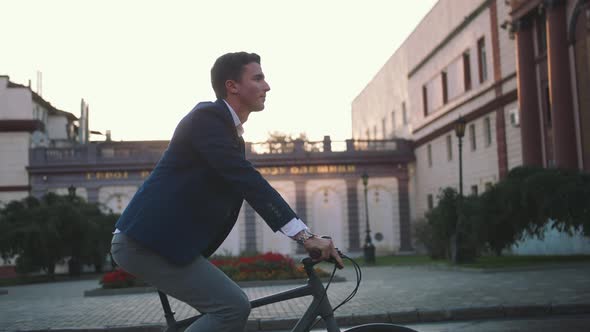 Handsome Young Man Driving His Bicycle on the Street in City Center During Sunrise