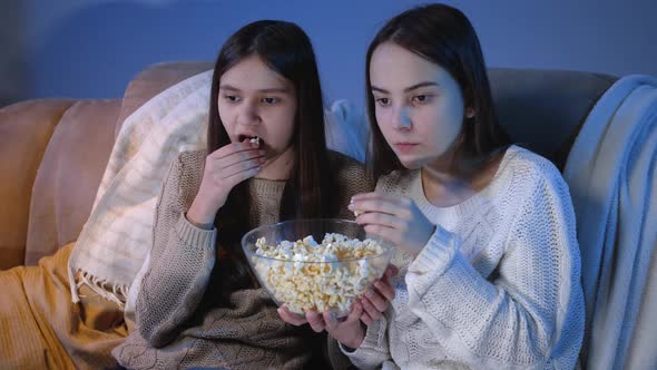 Happy Smiling Girls Enjoying Watching TV Show and Eating Popcorn at Night