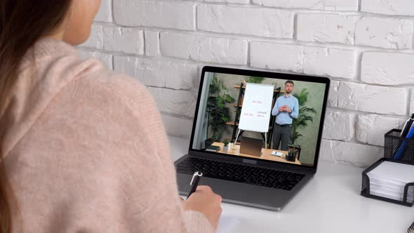 Businesswoman at Home Office Writes in Notebook Listen Online Video Call Laptop