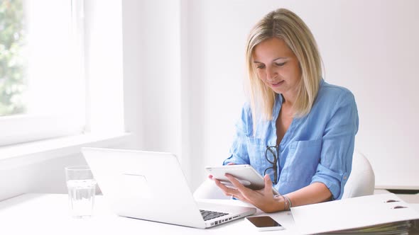 Businesswoman working with laptop and digital tablet in office
