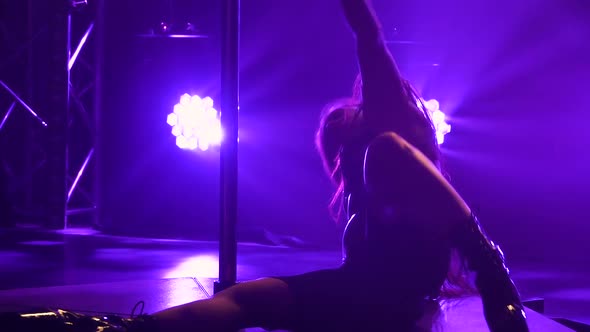 Striptease Dancer Moves Sexually While Lying on Floor Near Pole