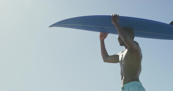 African American man holding a surfboard on his head