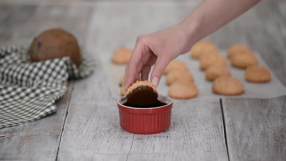 Dipping a Coconut Macaroon Cookie in Melted Dark Chocolate