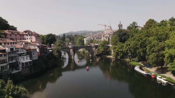 Aerial pan shot overlooking at tourists cruising on tamega river over Sao Goncalo bridge at daytime.