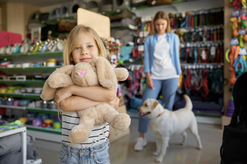 Little girl hugging soft bunny toy standing over pet store