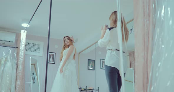 Beautiful and Pretty Girl is Trying on a Luxurious Wedding Dress in Front of a Mirror