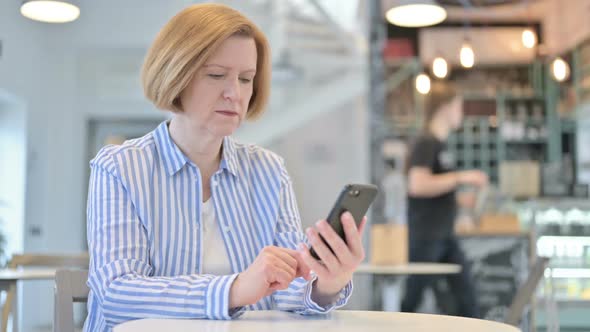 Loss on Smartphone By Creative Old Woman in Cafe