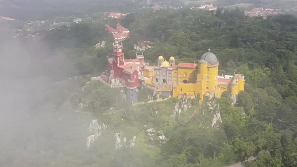 Aerial drone flying through the clouds orbiting around the Palacio da Pena in Portugal