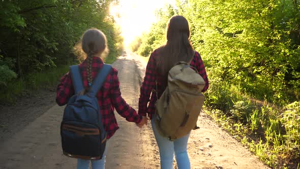 Hiker Girl. Girls Travel with Backpacks on a Country Road. Women Tourists Go To the Sunset. Happy