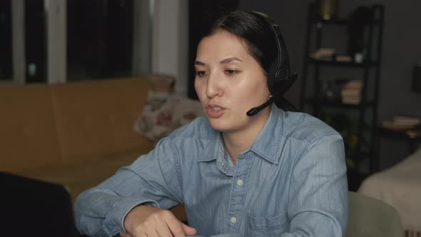 Side view Close-Up of a Young Asian Woman in Headphones with a Microphone Communicating 