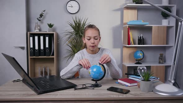 Modern Smart Good-Looking Teen Girl which Exploring the Little Globe with Magnifier in Her Room