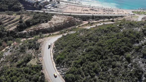 Trucks are riding on empty car road from mountains to coastline