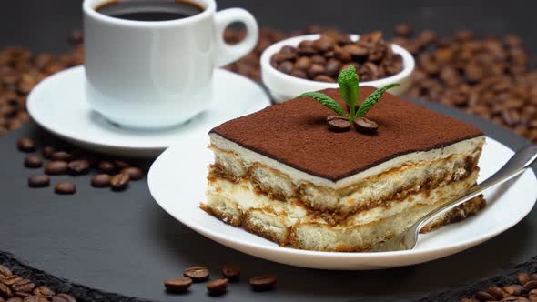 Portion of Traditional Italian Tiramisu dessert, cup of espresso coffee and coffee beans