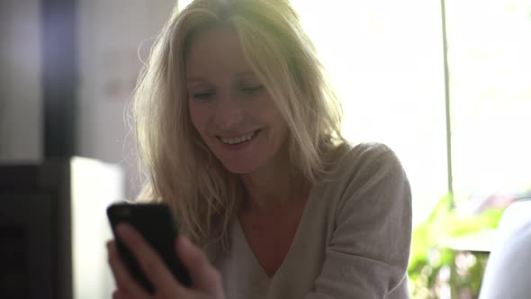 Mature woman texting on her smart phone at home