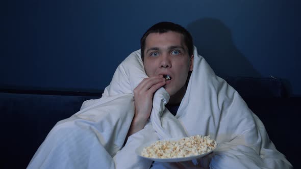 Handsome Caucasian Man Watches TV Movie Blanket Evening Eats Popcorn Sofa Home He Is Very Interested