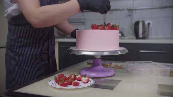 Confectionery  Pastry Chef Decorating Pink Cake with Strawberries