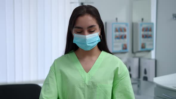 Portrait of Concentrated Professional Woman in Covid19 Face Mask Hanging Stethoscope on Shoulders in