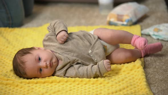 Little Baby Girl Lying Alone on Draw-Sheet While Mother Is Busy, Lack of Time