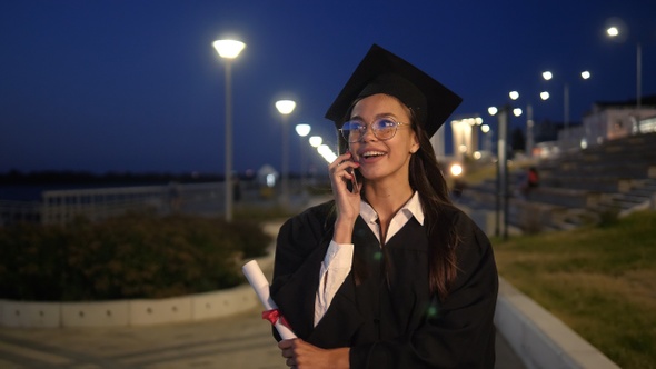 Young student dressed in black graduation gown walking