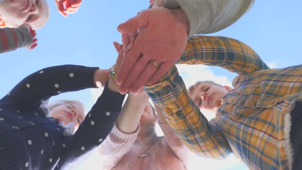 The Concept of Cohesion. Friendly Family Joins Hands Against the Blue Sky.