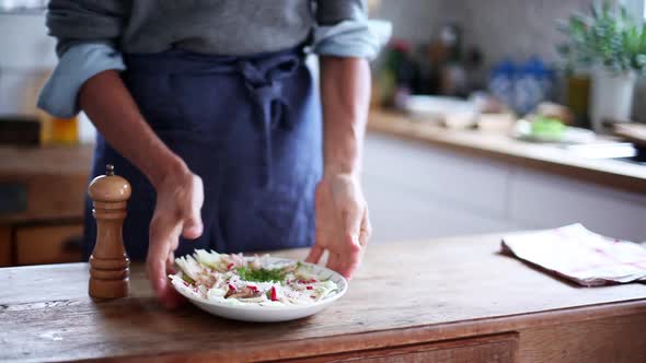 Woman grinding pepper over salad