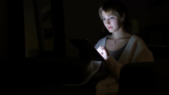 Woman Browsing Internet on Tablet at Night Scrolling