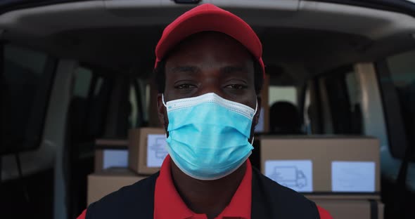 African man courier delivering packages with truck while wearing protective face mask