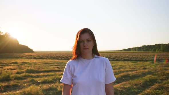 Female in the Frame the Camera Approaches the Field in the Background Sunset