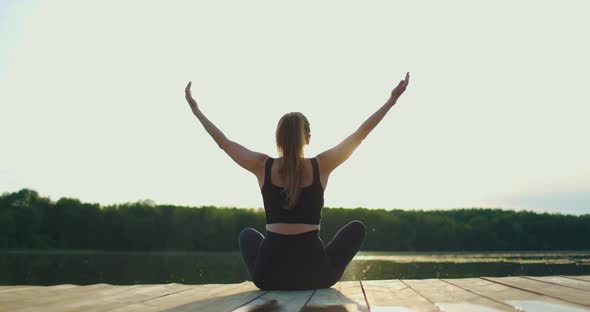 Young Woman Does Yoga on the Shore Oflake in the Fresh Air