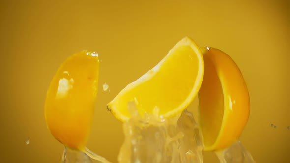 Closeup of Slices Orange Bouncing with Splashes of Juice on Yellow Background