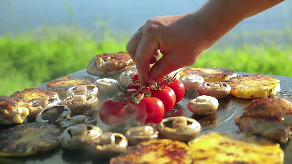 a Man Put a Branch of Grilled Tomatoes Next To Mushrooms and Pieces of Chicken with Pineapple