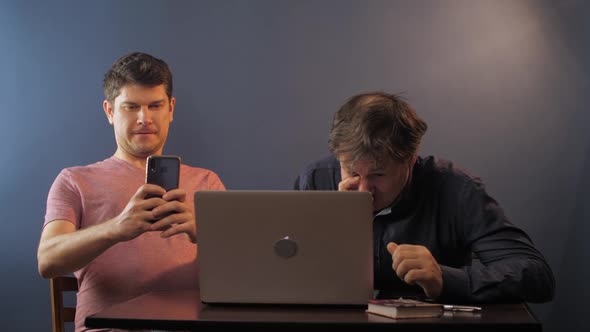 Man Takes Picture While Father Learns Use Computer at Table