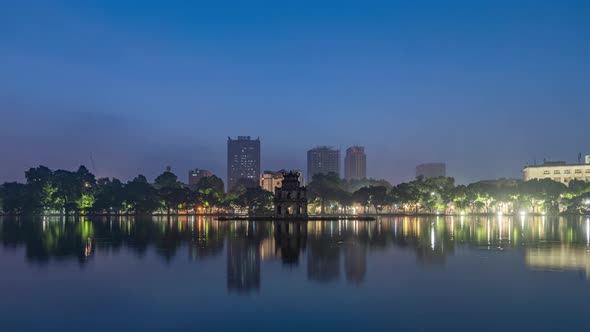 Time lapse of Turtle Tower Temple with skyscraper buildings and reflection in Vietnam.