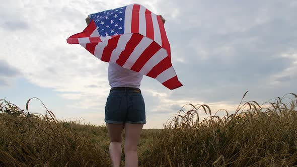 Patriotic Young Woman Holds the US Flag and Runs Across the Field