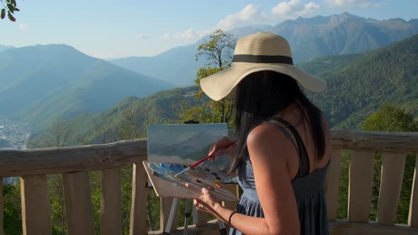 Female Artist Is Painting a Picture of Mountain Landscape