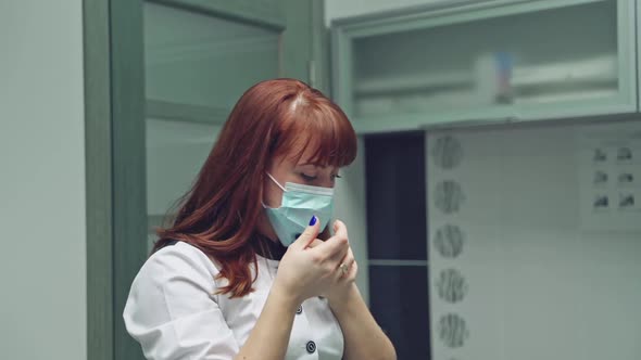 Dentist in a white robe is preparing for the procedure, wearing a mask and latex gloves