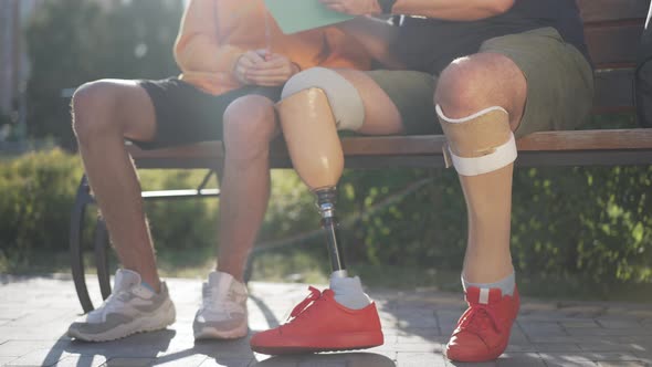 Artificial Prosthetic Limbs and Legs of Unrecognizable Father and Son Sitting on Bench Surfing