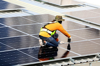 Technicians Install photovoltaic solar modules on roof of house.