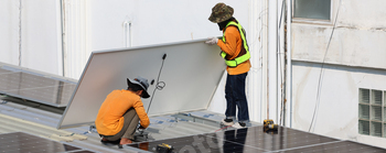 Technicians Install photovoltaic solar modules on roof of house.