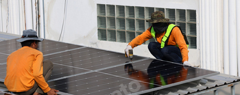 Technicians Install photovoltaic solar modules on roof of house.